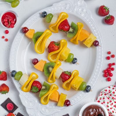 Spiedini di frutta con fragole, kiwi, uva, melone, ananas e peperone giallo su vassoio