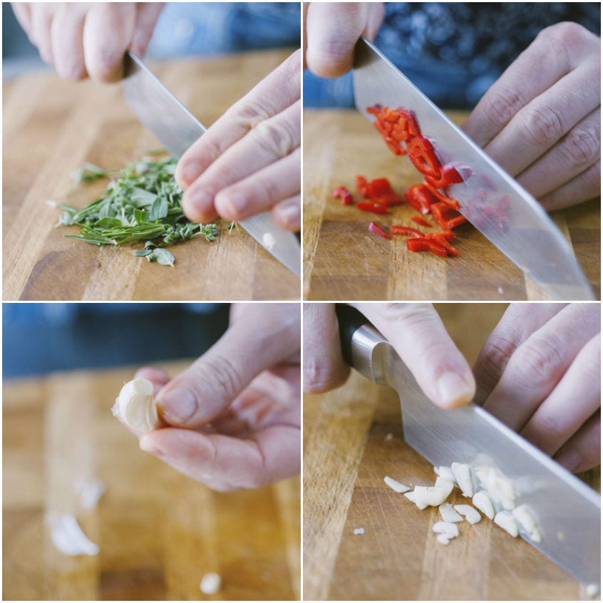 Erbe aromatiche, peperoncino e aglio tritati al coltello sul tagliere