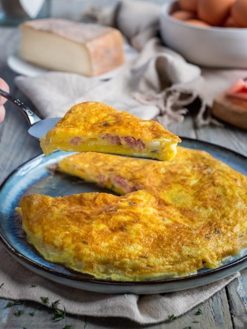 Frittata ripiena di cotto e taleggio con una fetta sollevata che mostra il ripieno filante