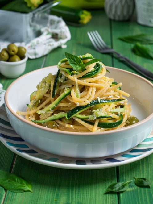 Pasta con le zucchine a julienne, formaggio grattugiato e foglie di basilico fresco