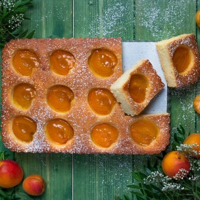 Torta di albicocche con mezze albicocche affondate nell'impasto e zucchero a velo, una fetta sollevata