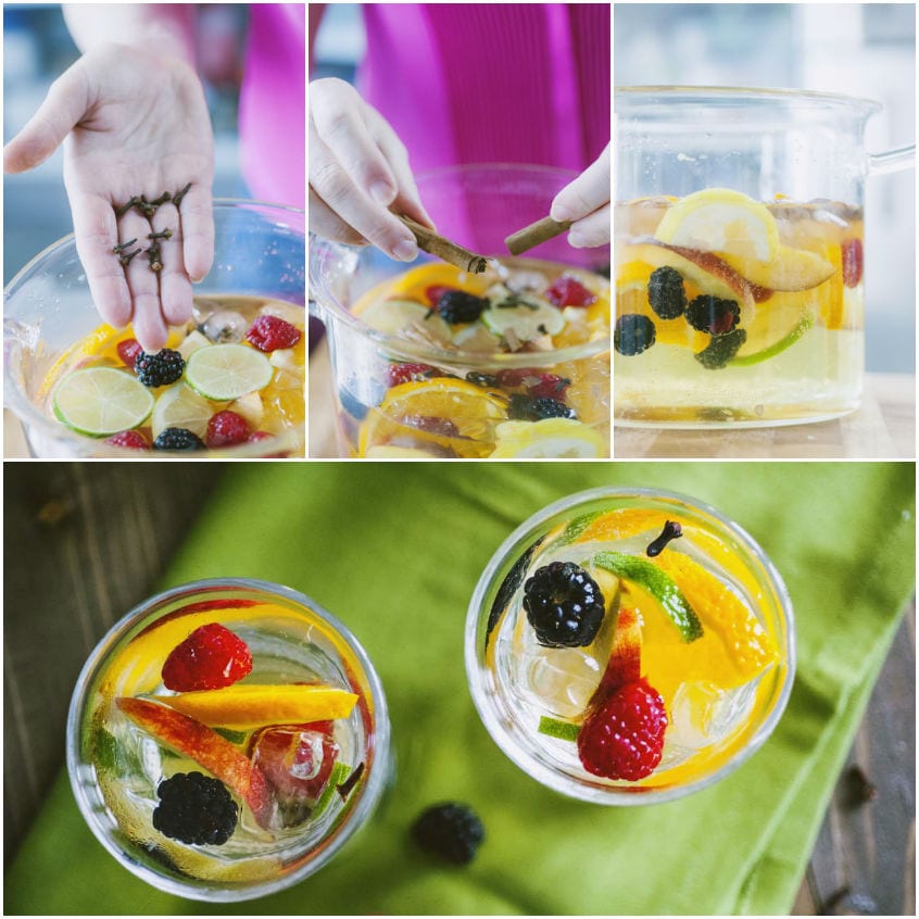 Sangria bianca con frutta a fette, frutti di bosco, chiodi di garofano e cannella in una caraffa di vetro