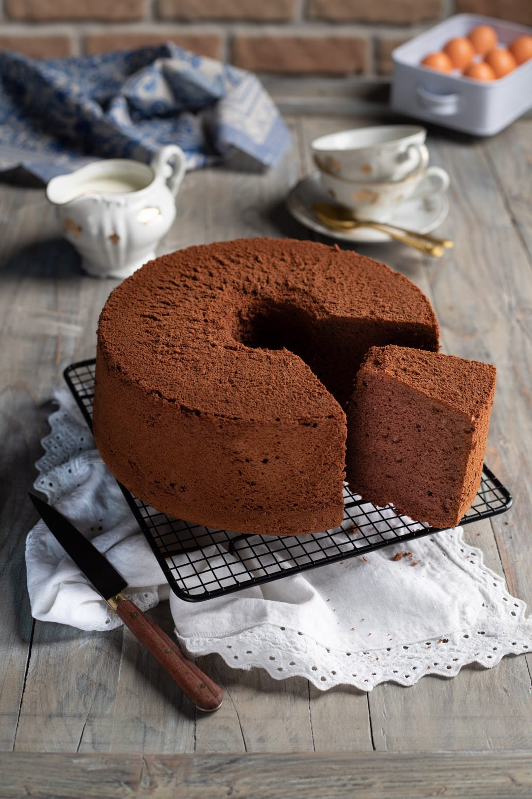 Chiffon cake al cacao su griglia con una fetta già tagliata che mostra l'interno soffice