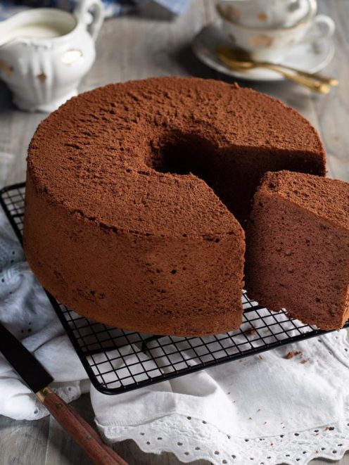 Chiffon cake al cacao spolverata di cacao amaro, con una fetta tagliata che mostra la mollica soffice