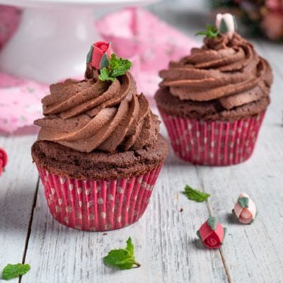Cupcake al cioccolato con frosting a spirale e roselline di zucchero e foglioline di menta