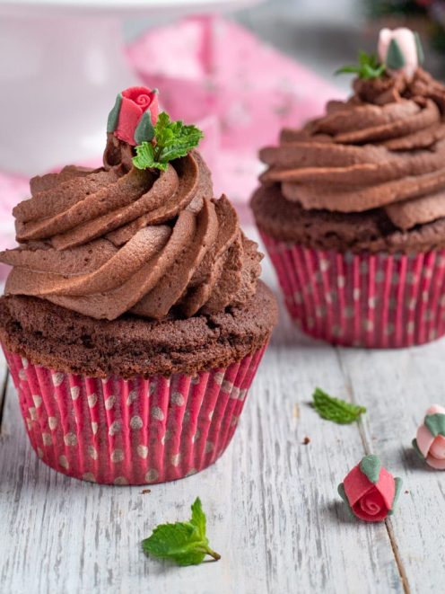 Cupcake al cioccolato con frosting a spirale e roselline di zucchero e foglioline di menta