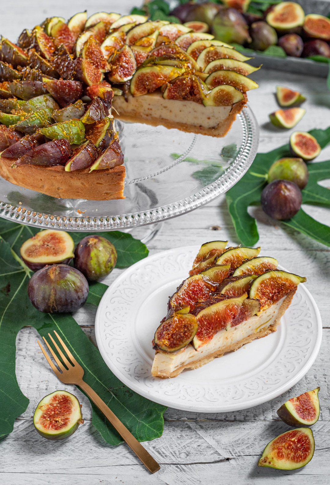 Fetta di crostata di ricotta e fichi caramellati servita accanto alla torta intera