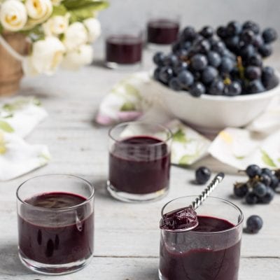 Sugoli serviti in bicchieri con uva nera fresca sullo sfondo