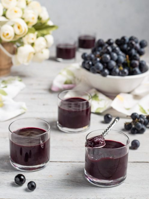 Sugoli serviti in bicchieri con uva nera fresca sullo sfondo