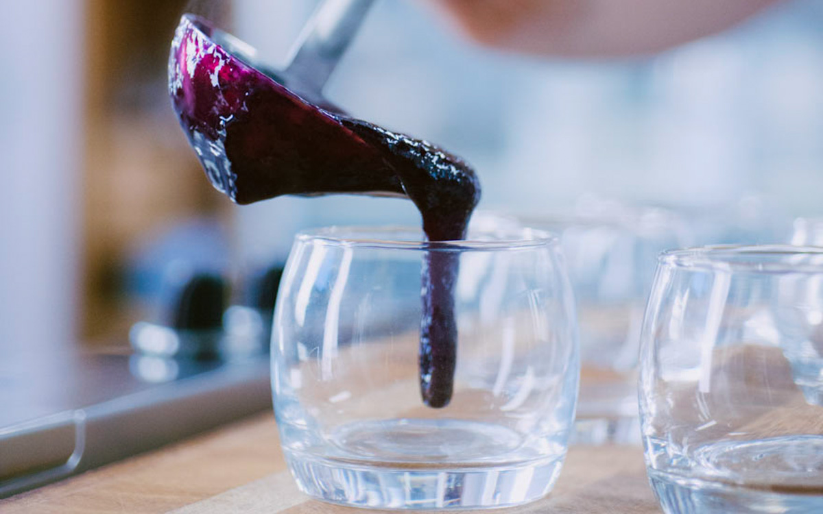 Composto scuro di uva fragola versato con un mestolo nei bicchieri