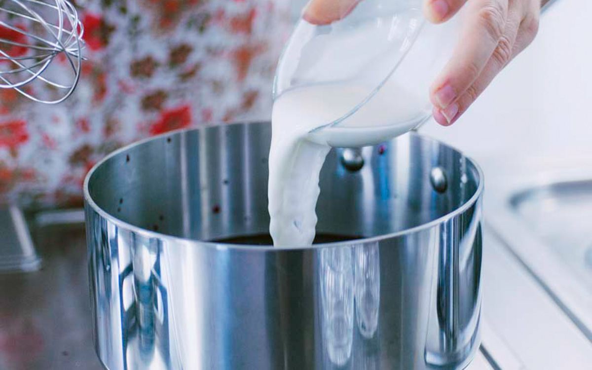 Latte versato a filo in una pentola per preparare i sugoli