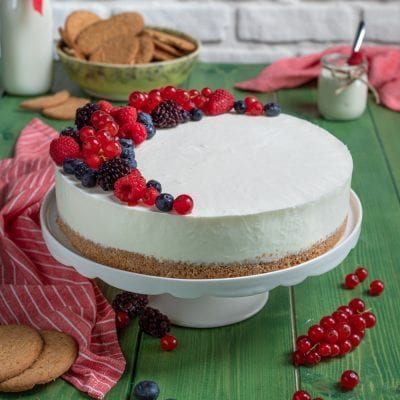 Torta fredda allo yogurt con base di biscotti e frutti di bosco freschi sulla superficie