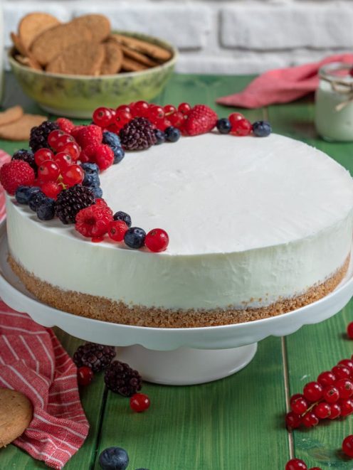 Torta fredda allo yogurt con base di biscotti e frutti di bosco freschi sulla superficie