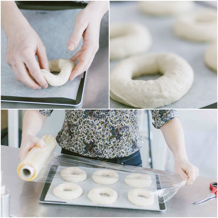 Bagel crudi formati a ciambella disposti su teglia e coperti con pellicola per la lievitazione