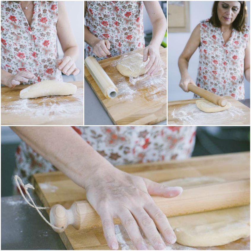 Mani che stendono la pasta frolla su un piano infarinato con il mattarello