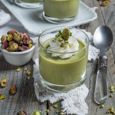 Cremoso al pistacchio servito in bicchiere, guarnito con panna montata e granella di pistacchi