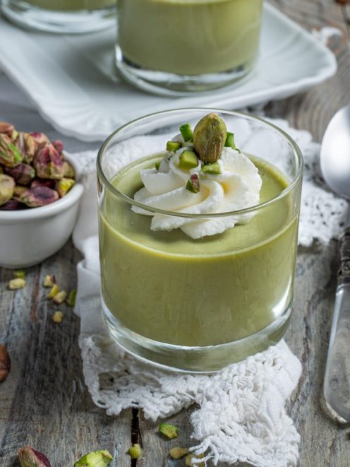 Cremoso al pistacchio servito in bicchiere, guarnito con panna montata e granella di pistacchi
