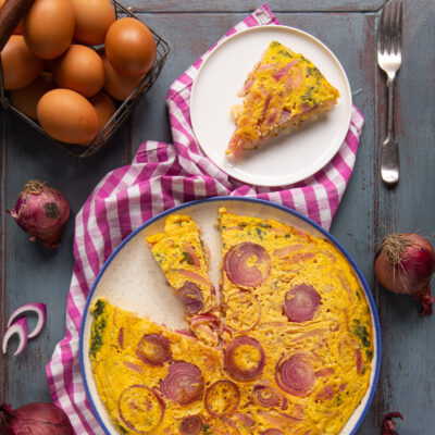 Frittata di cipolle rosse con una fetta già servita, dorata e ricca di anelli caramellati