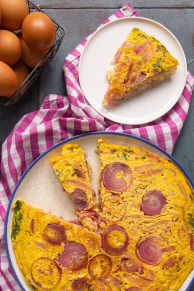 Frittata di cipolle rosse con una fetta già servita, dorata e ricca di anelli caramellati