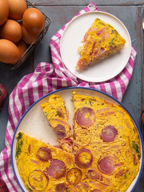 Frittata di cipolle rosse con una fetta già servita, dorata e ricca di anelli caramellati