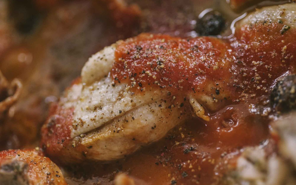 Petto di pollo alla cacciatora coperto di sugo al pomodoro denso e pepe nero macinato