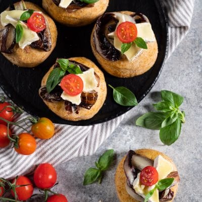 Focaccine integrali con radicchio arrostito, brie e pomodorini ciliegino guarnite con foglie di basilico