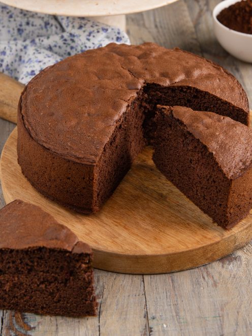 Pan di Spagna al cacao con una fetta tagliata che mostra la mollica soffice e compatta