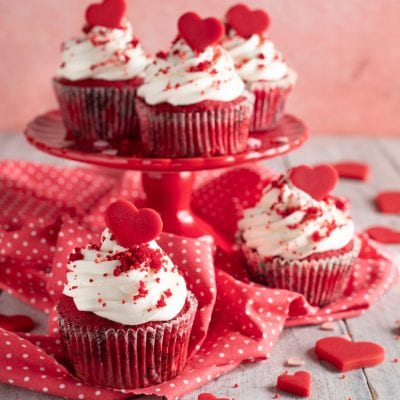 Red velvet cupcakes con ciuffo di glassa bianca, briciole rosse e cuoricino decorativo sopra