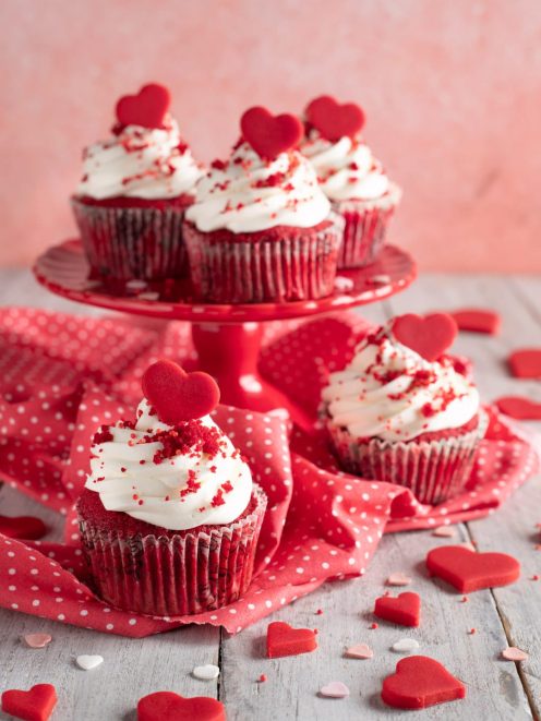 Red velvet cupcakes con ciuffo di glassa bianca, briciole rosse e cuoricino decorativo sopra
