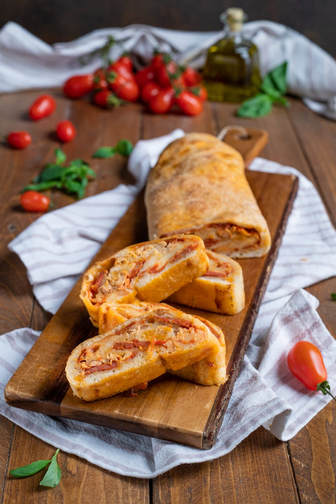 Rotolo di pizza affettato con ripieno di salumi e formaggio filante, servito su tagliere