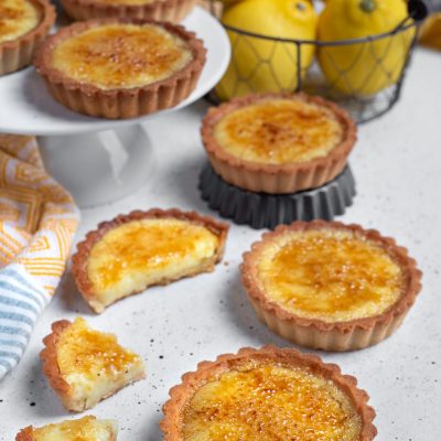 Tortine brulé al limone con crosta di frolla e superficie caramellata, una aperta a metà