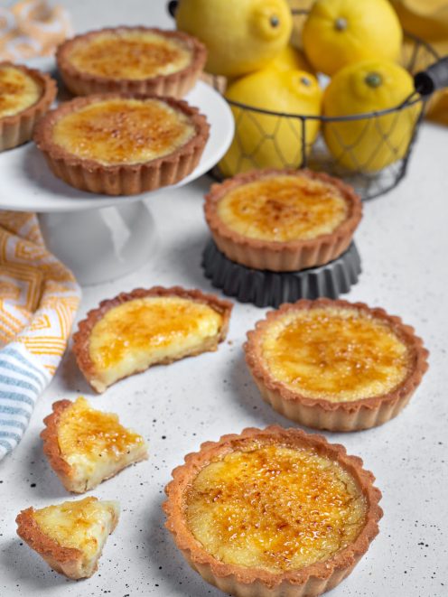 Tortine brulé al limone con crosta di frolla e superficie caramellata, una aperta a metà