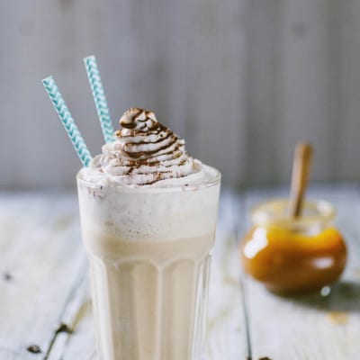 Frappè al cappuccino con panna montata e filo di cioccolato, servito con due cannucce