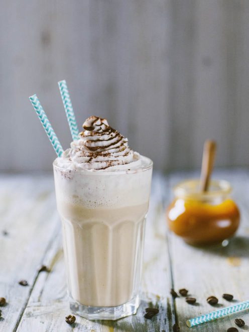 Frappè al cappuccino con panna montata e filo di cioccolato, servito con due cannucce