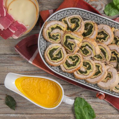Arrotolato ripieno affettato con farcia di spinaci e frittata, servito con salsa allo zafferano