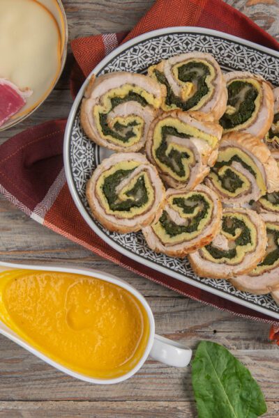 Arrotolato ripieno affettato con farcia di spinaci e frittata, servito con salsa allo zafferano