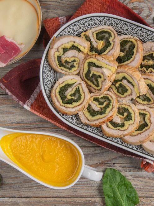 Arrotolato ripieno affettato con farcia di spinaci e frittata, servito con salsa allo zafferano