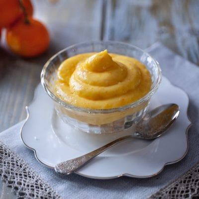 Crema pasticcera al mandarino servita in coppetta di vetro con cucchiaino d'argento