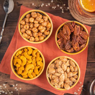 Frutta secca da aperitivo in quattro ciotole con nocciole, pecan speziate, anacardi al curry e mandorle
