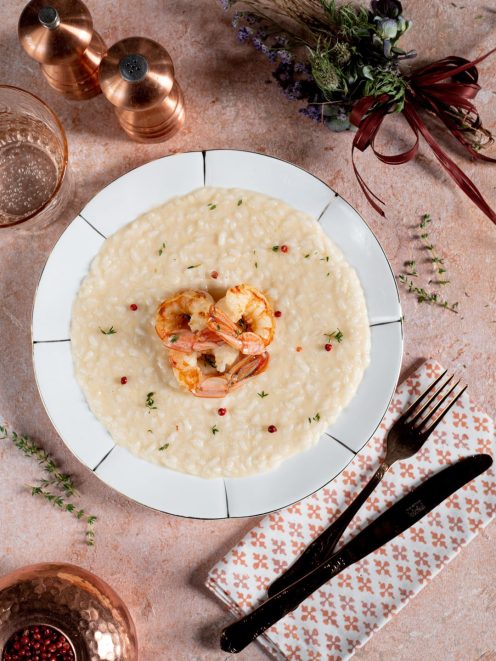 Risotto allo champagne e gamberi, decorato con pepe rosa in grani