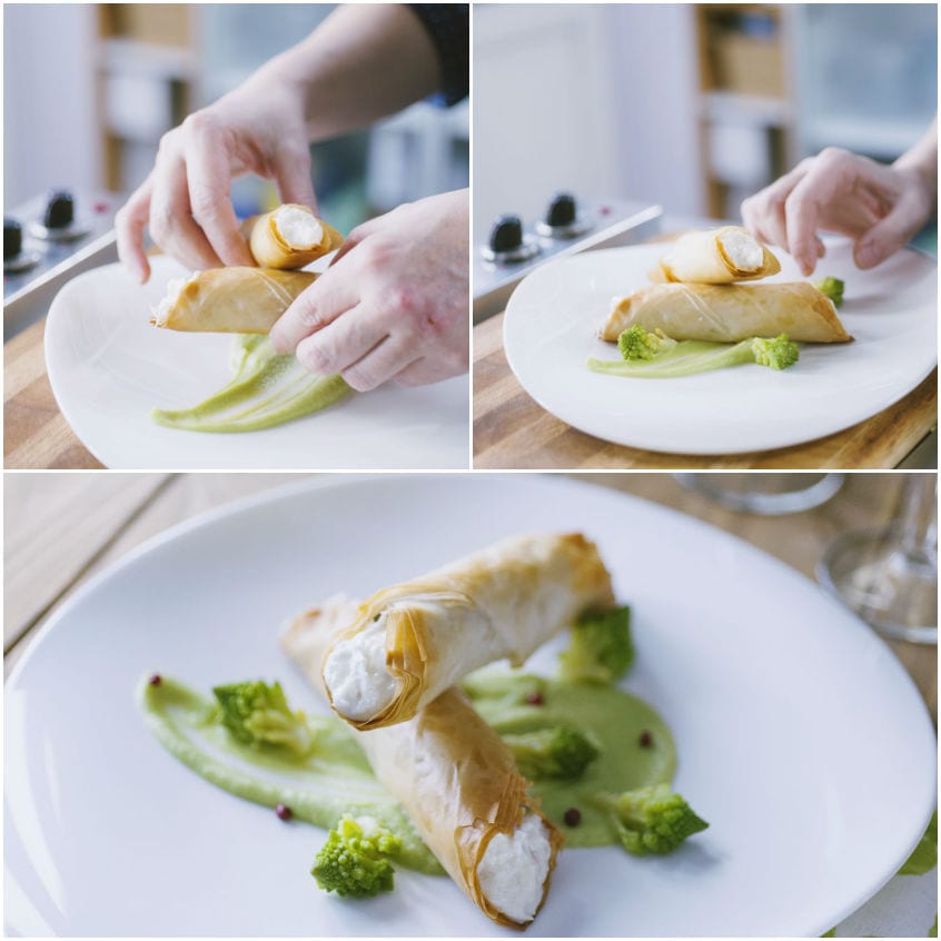 Mani che posizionano i cannoli croccanti sul piatto con crema verde e broccolo romanesco