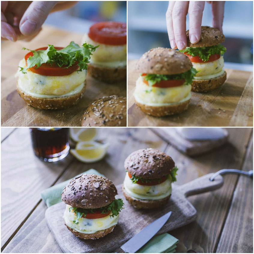 Mani che chiudono i miniburger di baccalà con lattuga, pomodoro e uovo su panino ai cereali