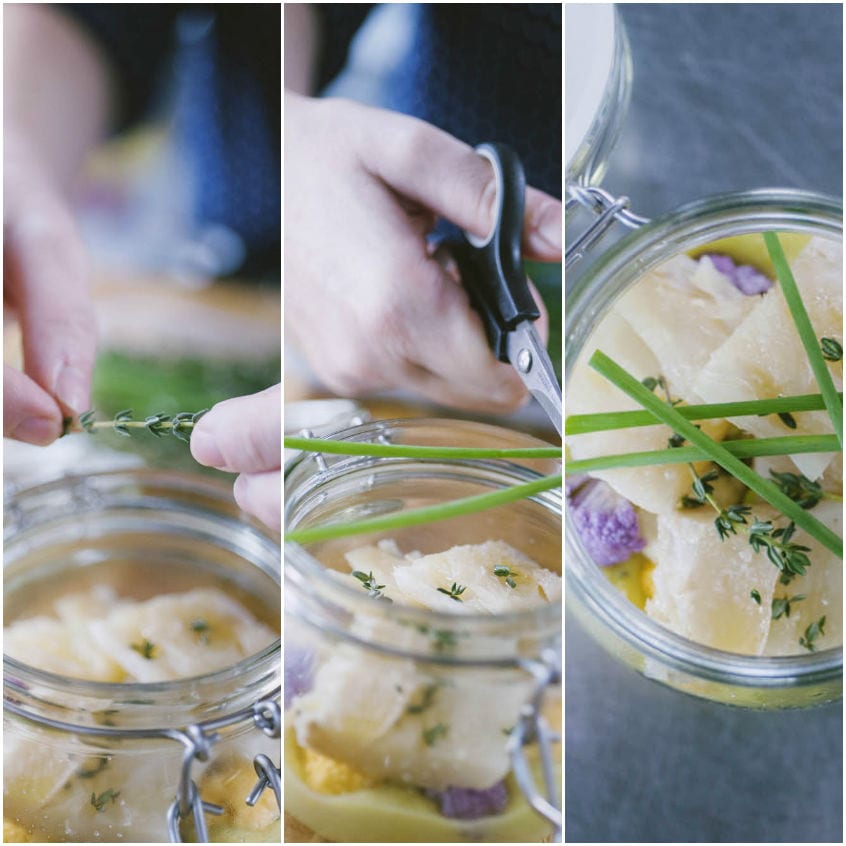 Erba cipollina tagliata con le forbici sul vasetto di stoccafisso con timo e fiori di cavolfiore