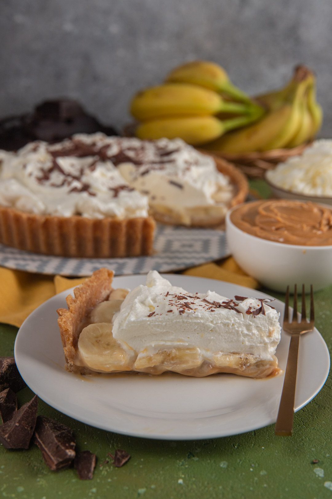 Fetta di banoffee pie con banane, panna montata e scaglie di cioccolato fondente