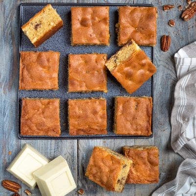 Blondies tagliati a quadrotti su teglia con noci pecan e cioccolato bianco a pezzi