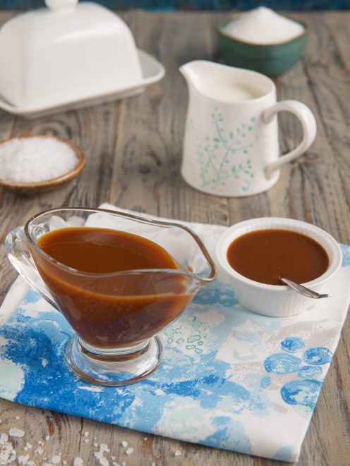 Salsa al caramello salato densa e lucida servita in una salsiera di vetro con ciotolina a lato