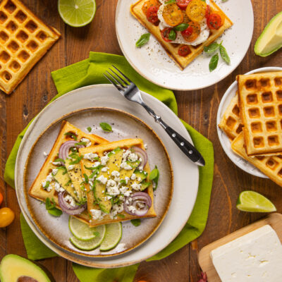 Waffle salati con avocado a fette, cipolla rossa, feta sbriciolata e foglie di menta fresca