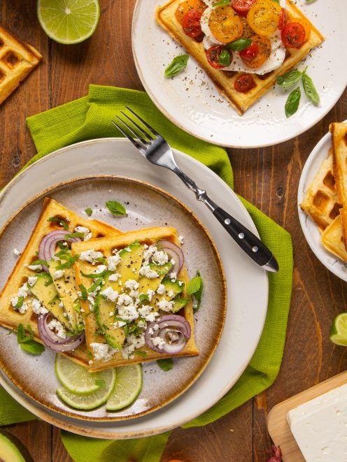 Waffle salati con avocado a fette, cipolla rossa, feta sbriciolata e foglie di menta fresca