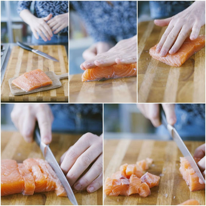 Filetto di salmone tagliato prima a listarelle poi a piccoli cubetti su tagliere di legno