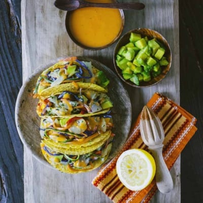 Tacos con stoccafisso e verdure sfilacciate, conditi con maionese al pomodoro e serviti con avocado a cubetti